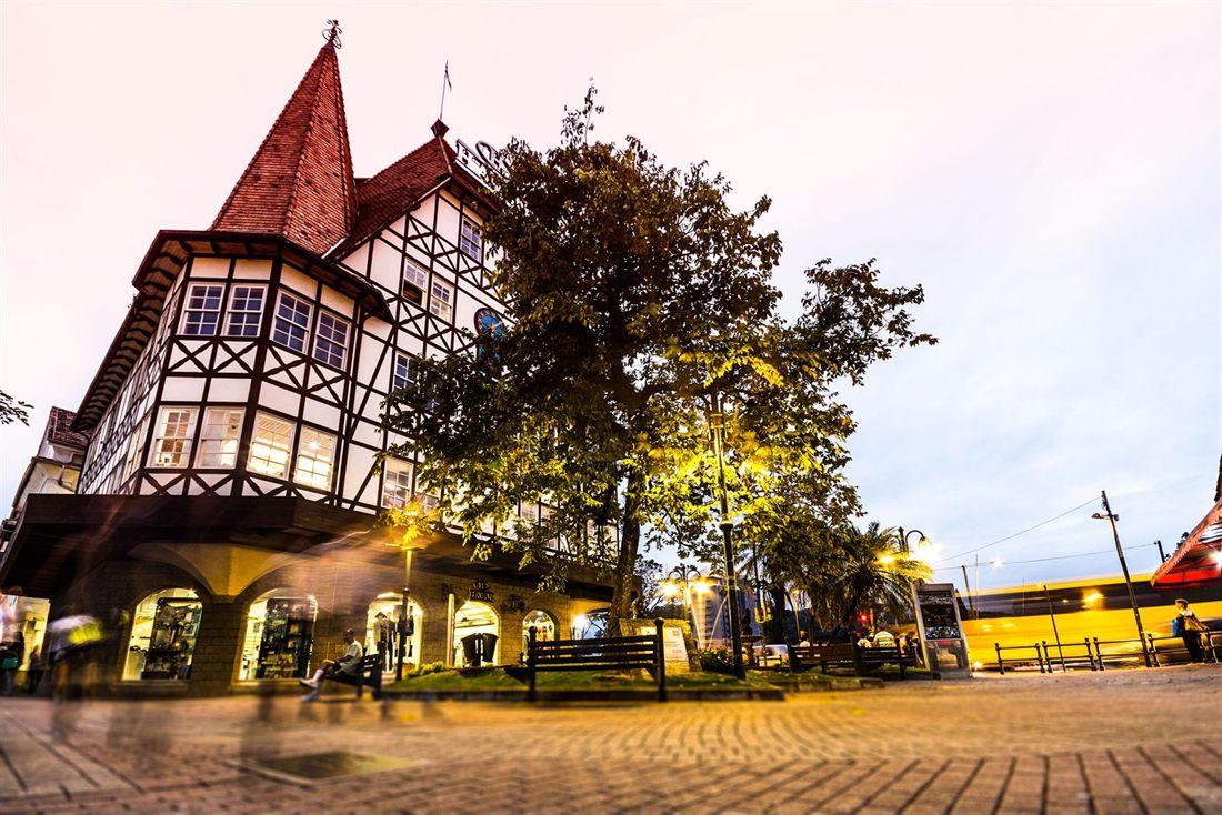 The Castelinho, a half-timbered building with a steep tiled roof, lit at nightfall on Rua XV de Novembro