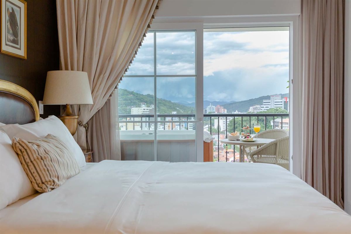 A suite at the Villa do Vale: the bed, and through the glass door the balcony and the city beyond